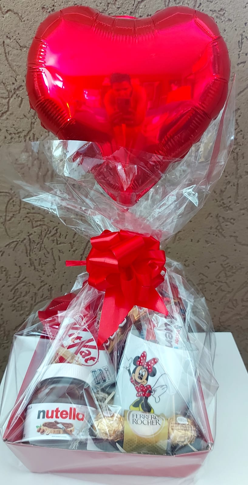 Cesta para presente, com um balão de coração vermelho, caneca da minnie, e muito chocolate
